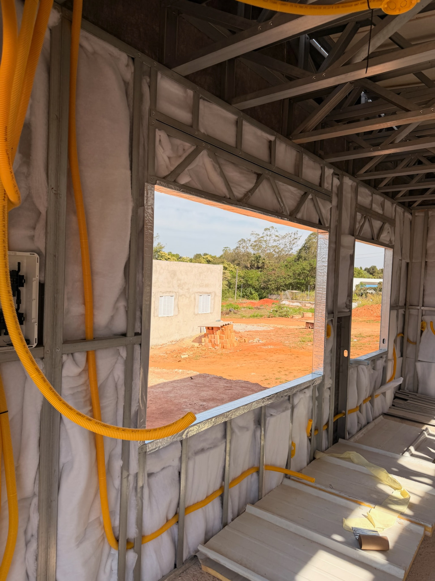 Interior da obra com preenchimento em manta, instalações elétricas e hidráulicas sendo realizadas dentro das paredes em Light Steel Frame